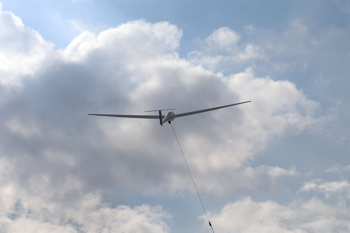Ein Segelflugzeug wird an einem Seil in den Himmel gezogen, umgeben von Wolken.